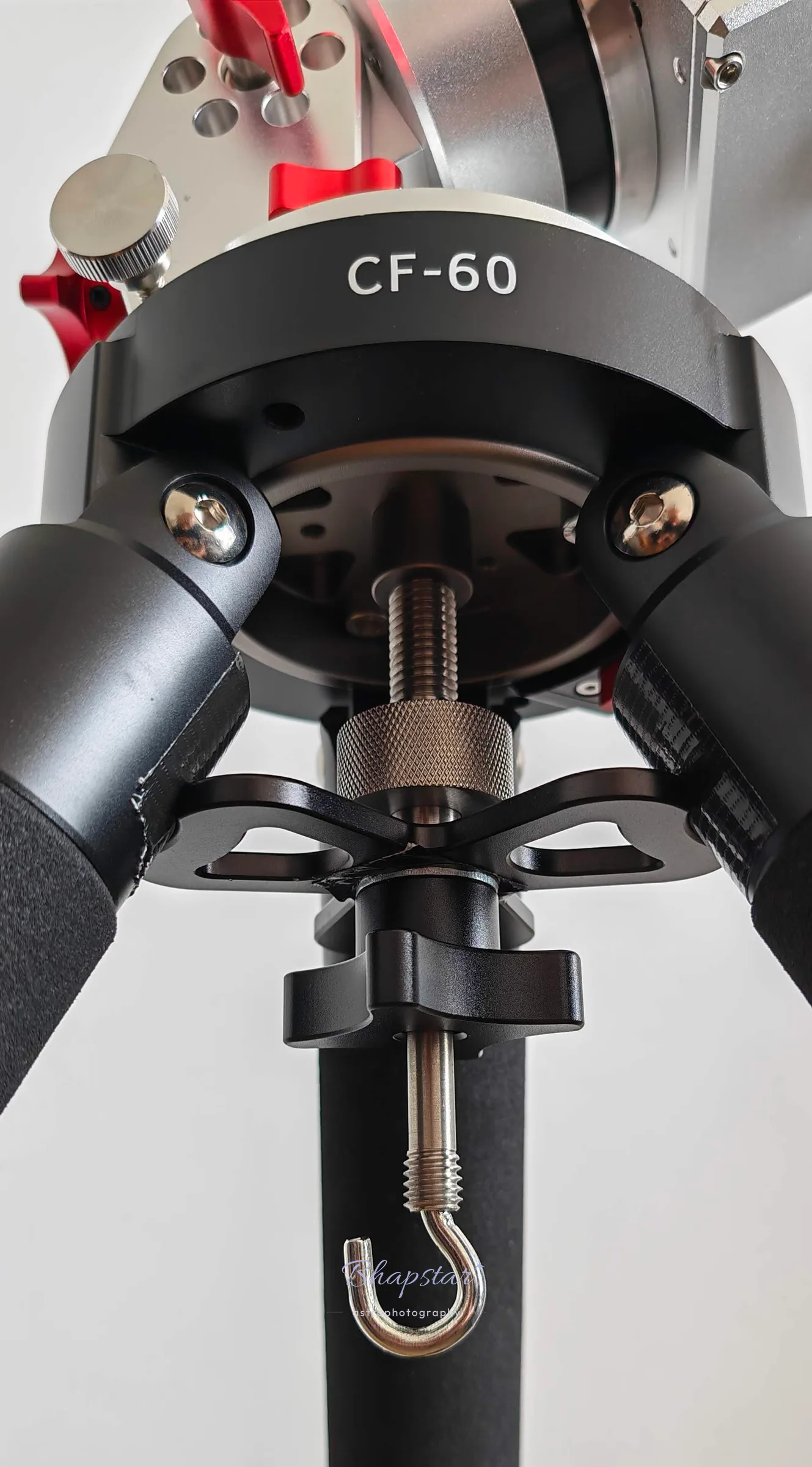 Underside of the CF-60 top plate with a mount fitted, showing the central threaded rod, the triangular brace and the sandbag hook