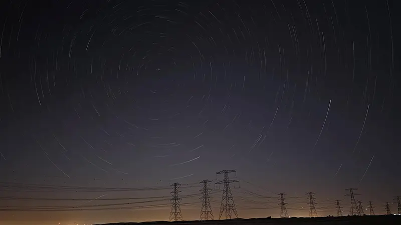 Circumpolar star trails wheeling around the north celestial pole above a line of desert pylons